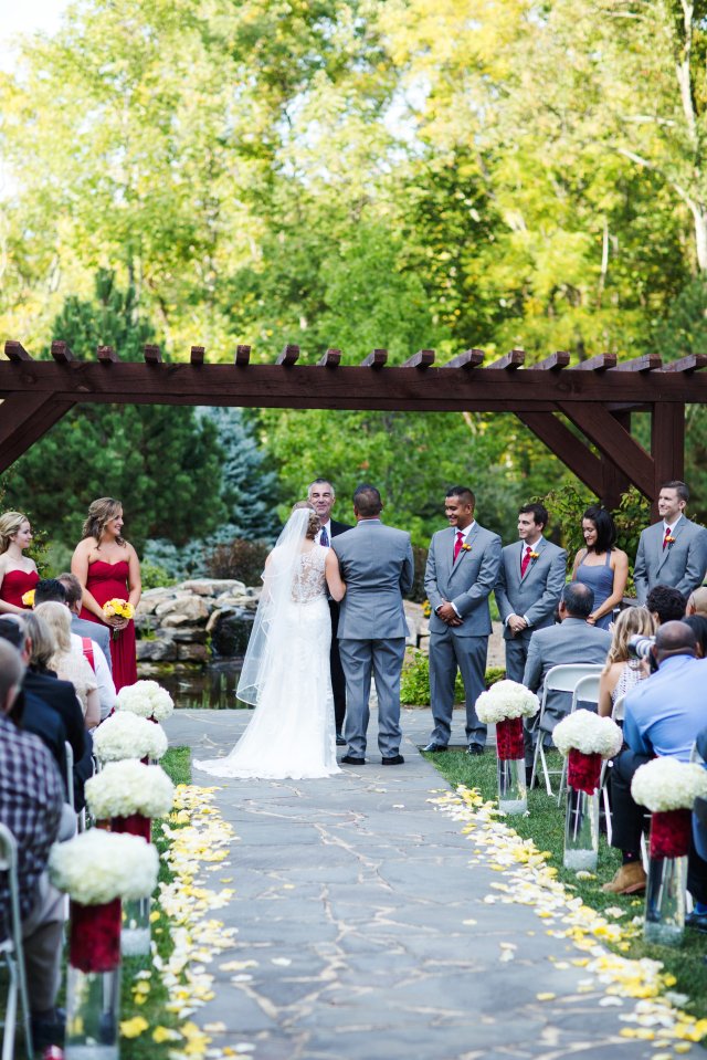The ceremony site featured tall, glass vases with red flower petals and white hydrangeas.
