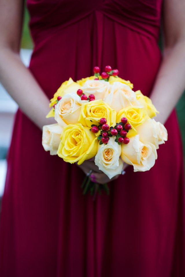 The bridal party carried yellow and peach roses with red hypericum berries.